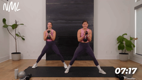 two women performing cossack lateral squats in an inner thigh workout at home