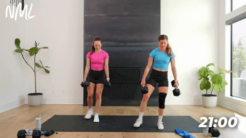 two women performing dumbbell curtsy lunges in a leg workout