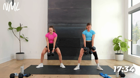 two women performing dumbbell sumo squats in a leg workout