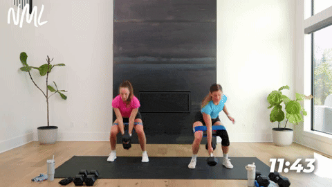 two women performing banded squat jacks in a leg workout