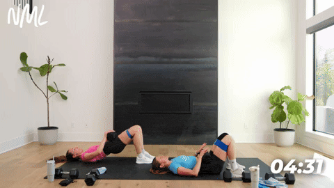 two women performing dumbbell glute bridges in a leg workout