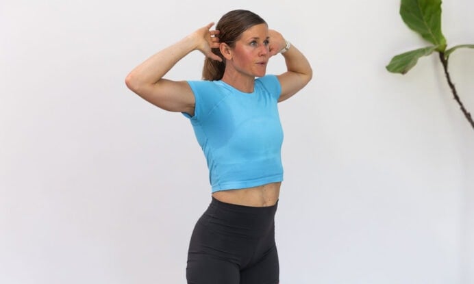 Woman performing standing cat/cow as part of active recovery workout
