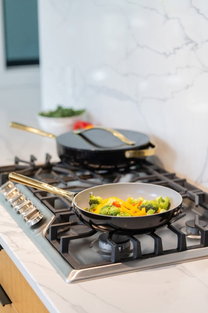 Two caraway cookware saute pans on a stove.
