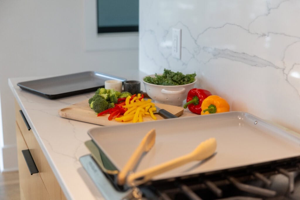 Caraway cookware extra large sheet pan with chopped veggies as part of a sheet pan meal.