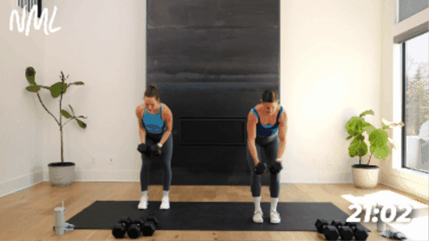 standing women performing back fly exercise as part of arm workout with dumbbells