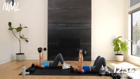 women laying on their backs performing a dumbbell chest press