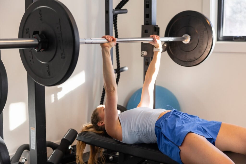 woman performing chest press in garage gym
