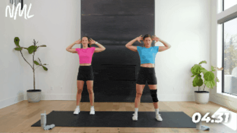two women performing standing shoulder CARs as part of active recovery workout