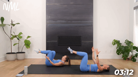 two women demonstrating a pilates teaser from the mat in a pilates workout