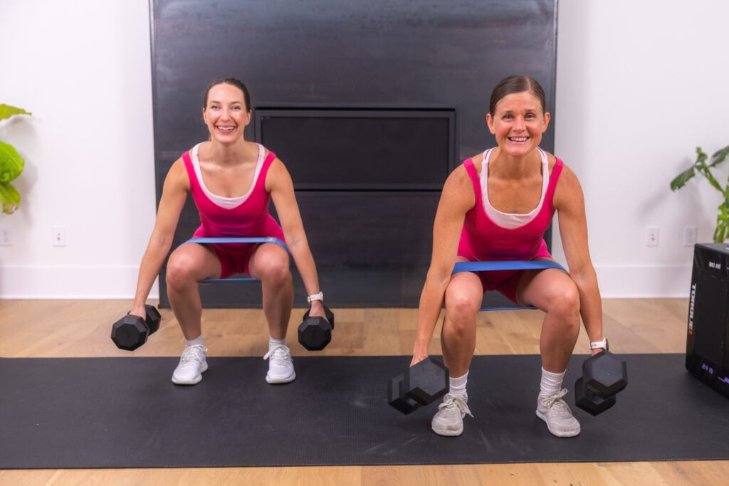 two women performing dumbbell squats in an at home glute workout