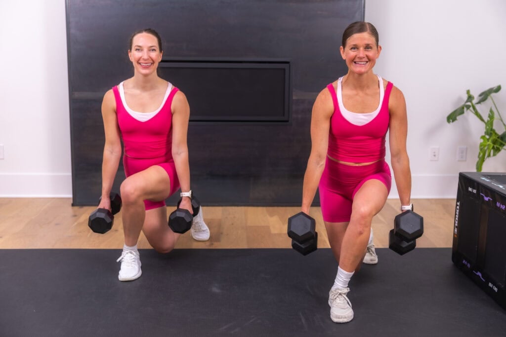 two women performing curtsy lunges with dumbbells in an at home glute workout