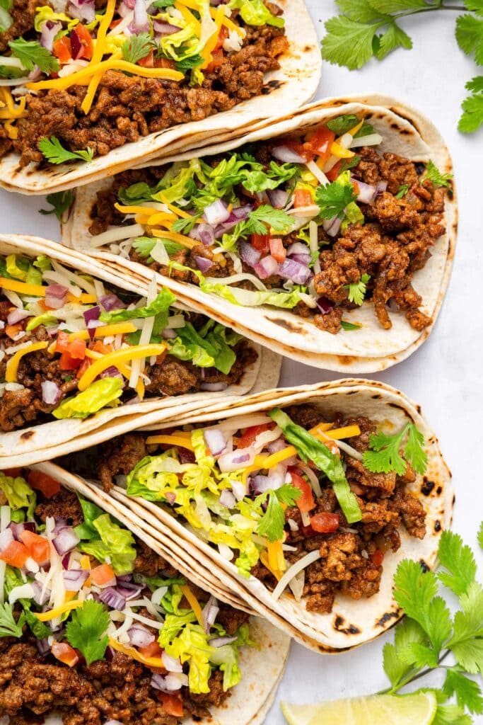 Ground Beef Tacos with ground beef, onions, cheese, shredded lettuce, shredded cheese and flour wraps. 