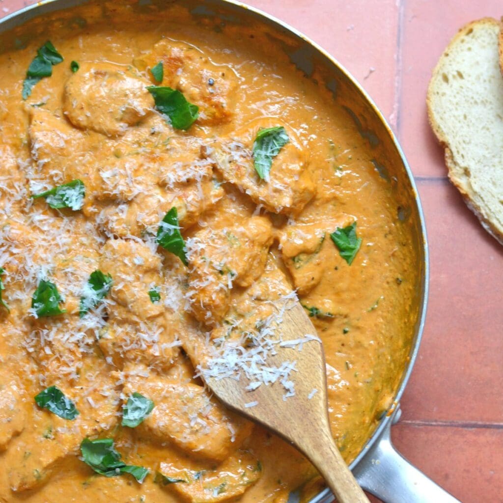 Tuscan Chicken with a creamy sauce in a pan as part of a high protein dinner post. 
