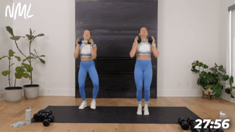 two women performing press jacks with one dumbbell as part of hiit workout at home