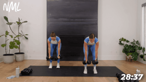 standing women performing a row, curl and press with dumbbells