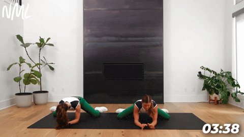 two women demonstrating frog rocks as part of leg stretches before a workout