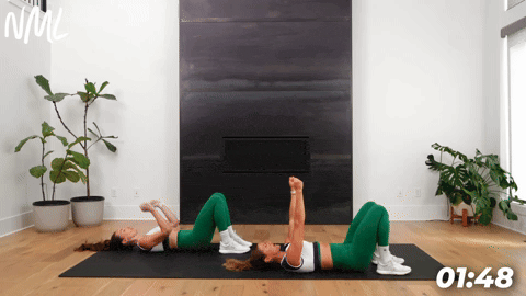 two women demonstrating a bodyweight glute bridge as part of leg stretches before a workout