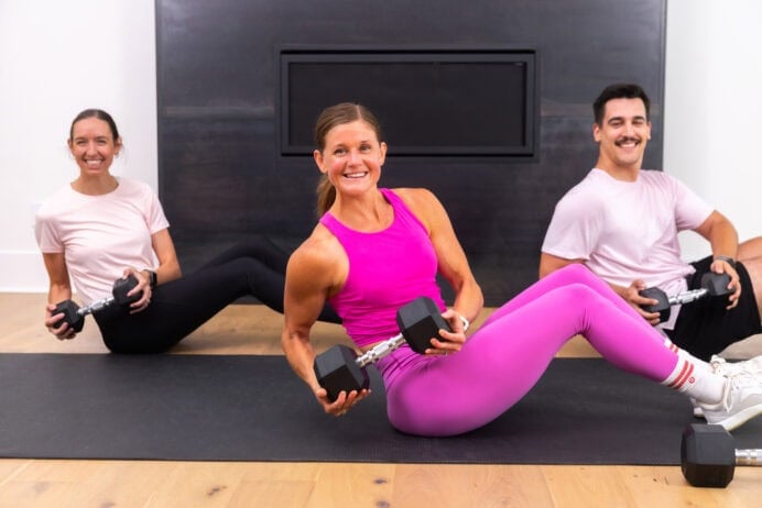 three people performing a seated dumbbell twist in a full body dumbbell workout