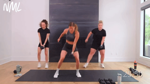 Two women performing side to side squat hops with one dumbbell. One women performing side to side squats.