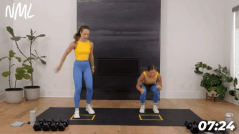 people performing surfer squat exercise in  a living room with black fireplace