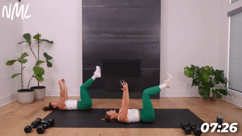 two women performing a dumbbell dead bug in a dumbbell core workout
