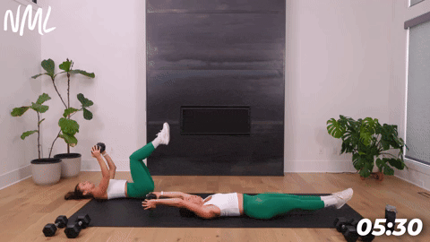 two women performing a hollow rock hold and reverse crunch in a dumbbell core workout
