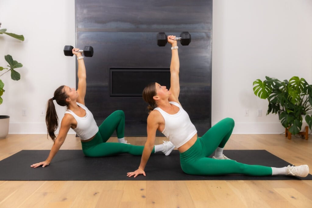 two women demonstrating a half turkish get up in a dumbbell core workout