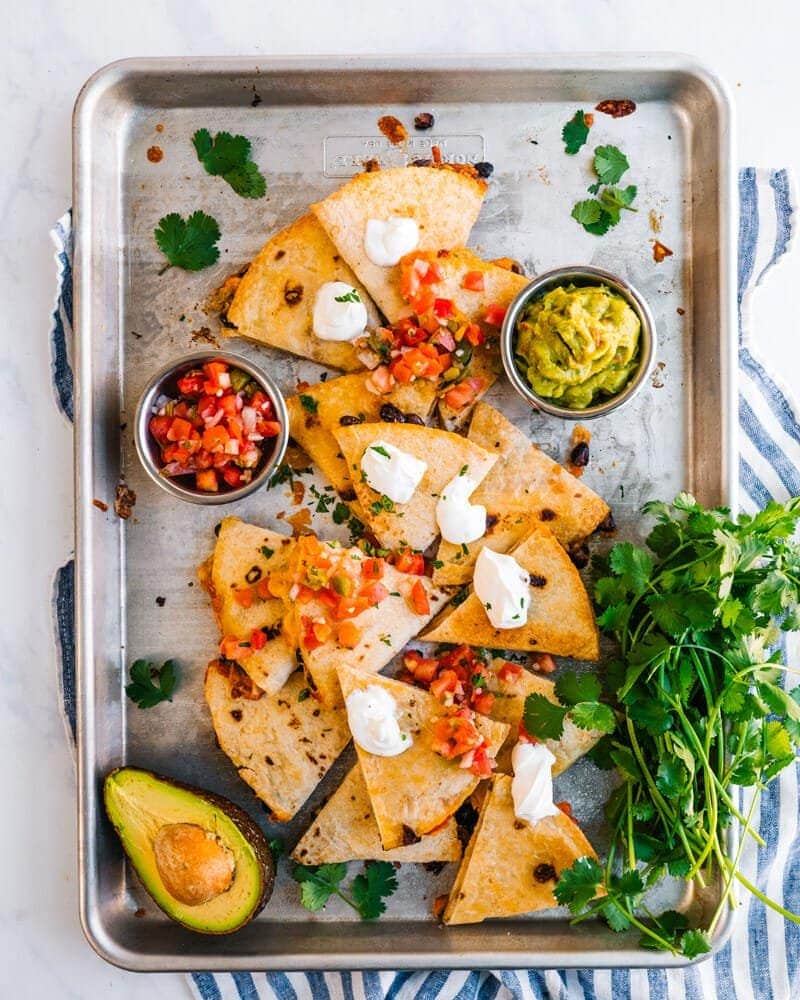Sheet pan baked Quesadilla with quad, avocado, mini tacos, sour cream and diced tomatoes.