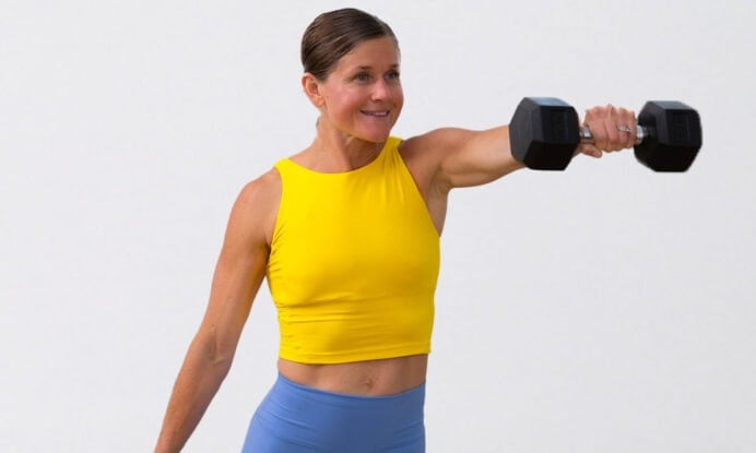 woman lifting dumbbell to eye level as part of full body cardio strength workout