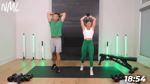 Male and female performing a Overhead Tricep Extensions with one dumbbell as part of a chest shoulder tricep workout. 