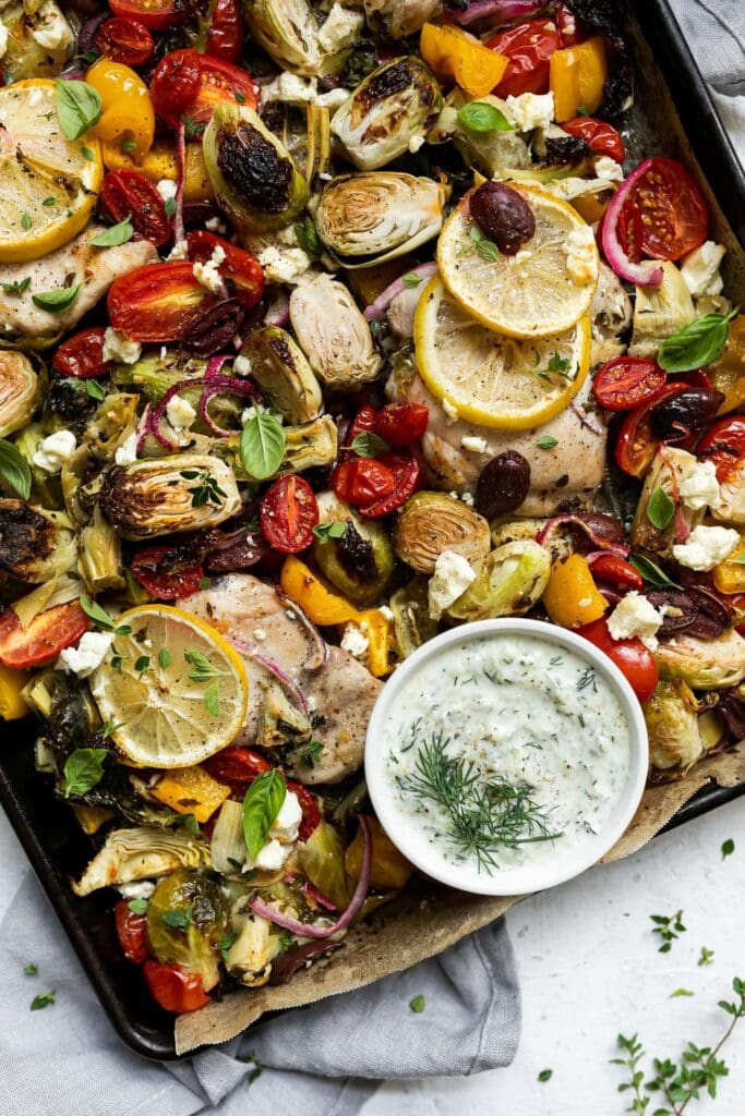 Sheet Pan Greek Chicken and Veggies With Tzatziki with tender vegetables and chicken thighs.