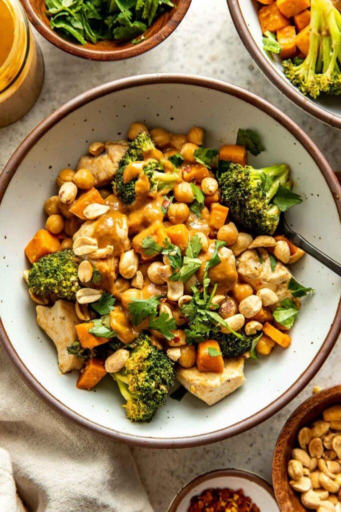 Thai Peanut Sweet Potato Bowls With Chicken with sweet potatoes, Broccoli florets, Chickpeas, Chicken breast, Roasted peanuts and homemade peanut dressing.