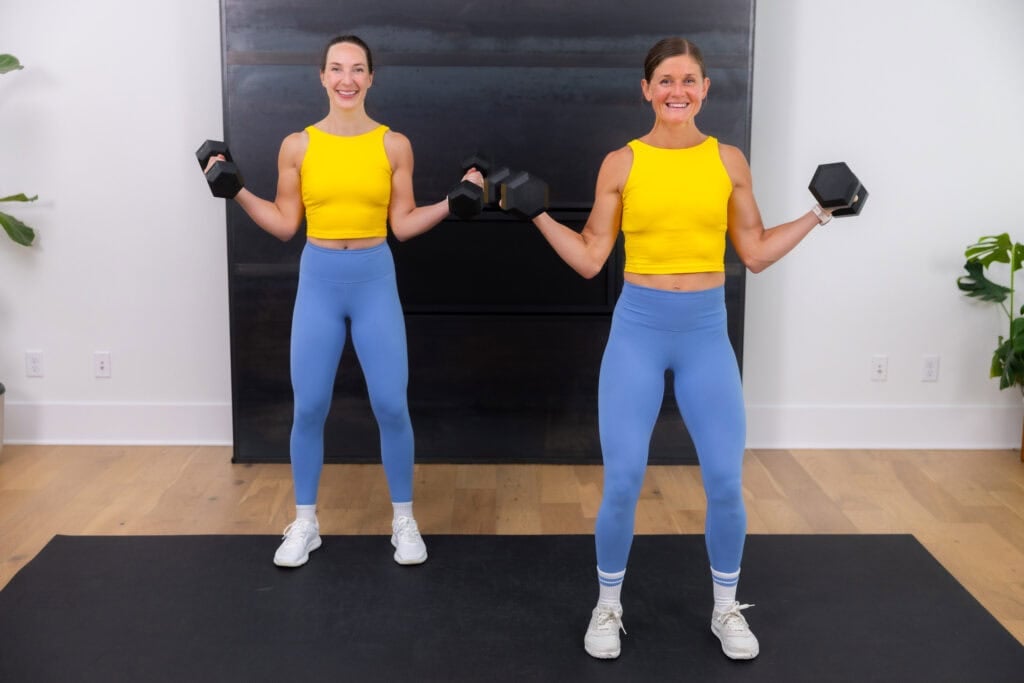 two women performing bicep curls as part of cardio strength workout