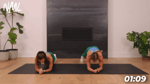 example of forearm plank extensions on black exercise mat in front of fireplace 