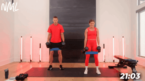 man and women performing banded squats against a dark fireplace as part of at home leg and glute workout