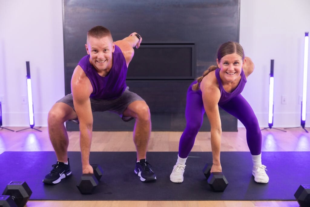 male and female performing a squat hold as part of a full body dumbbell only workout.
