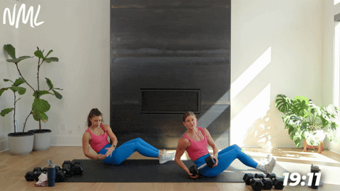two women demonstrating a seated twist in a full body strength circuit workout