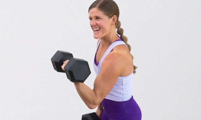 woman smiling and performing bicep curl as part of arms and abs workout