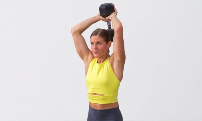 woman performing overhead tricep extension as part of quick full body workout at home