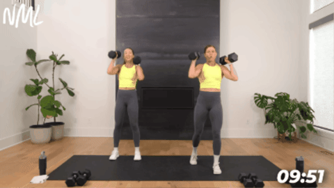 women performing an alternating overhead press with dumbbells as part of quick workout