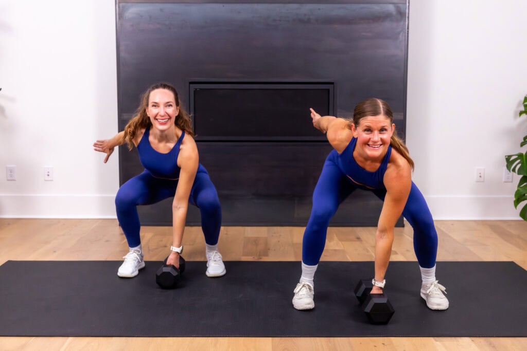 two women at the bottom of a dumbbell snatch as part of leg superset workout