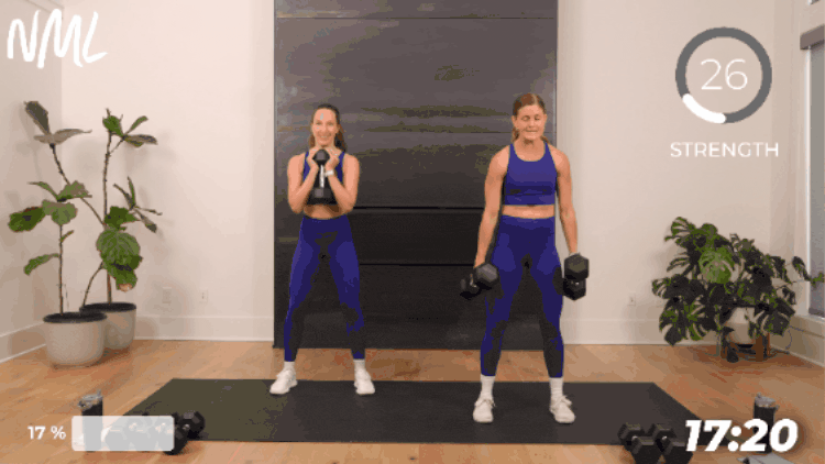 two women performing a squat with dumbbells as part of leg superset workout