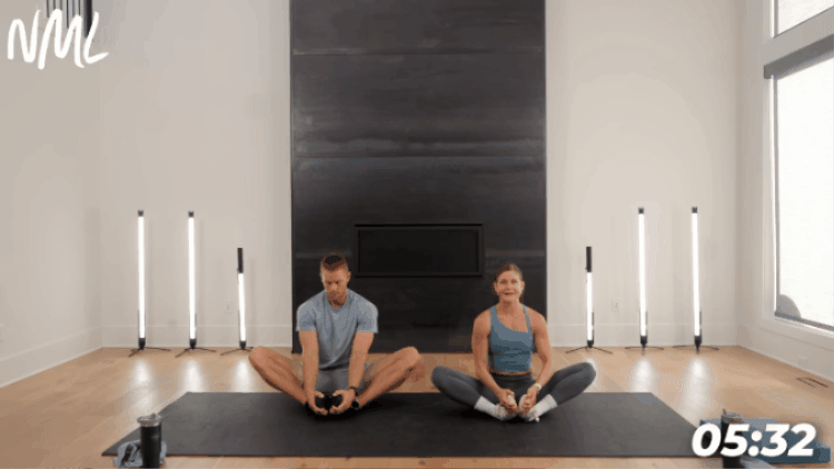 adults sitting on black workout mat performing butterfly stretch