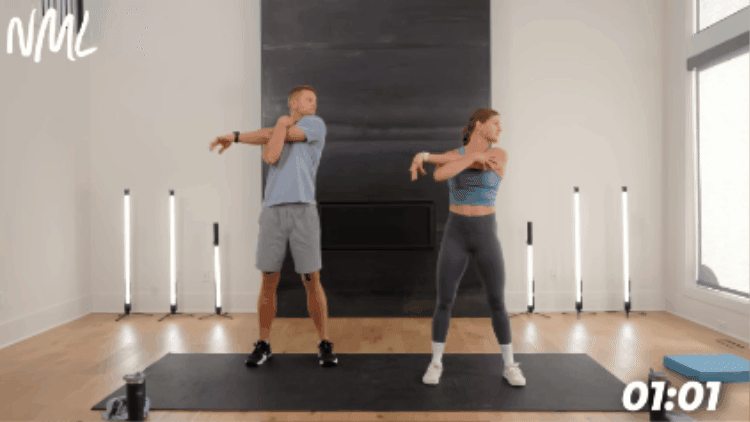 standing couple performing a shoulder and tricep stretch as part of cool down stretches example