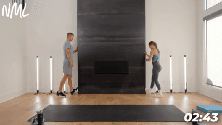 man and woman performing calf stretch against wall as part of stretching routine