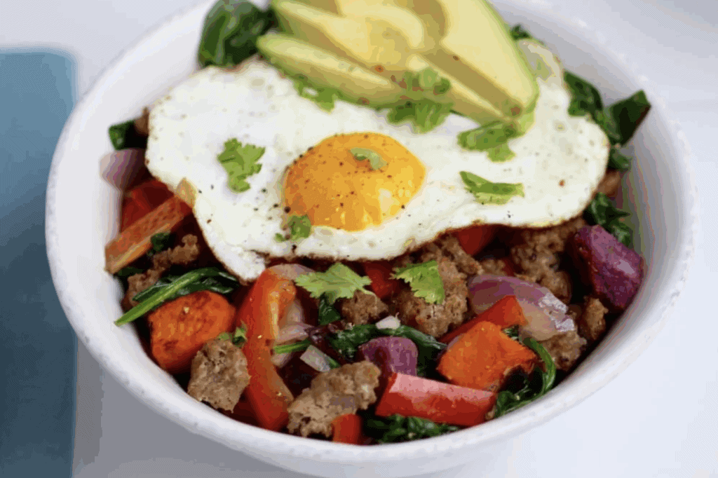 Sweet potato hash with eggs, turkey sausage links, greens, peppers, red onion and avocado.