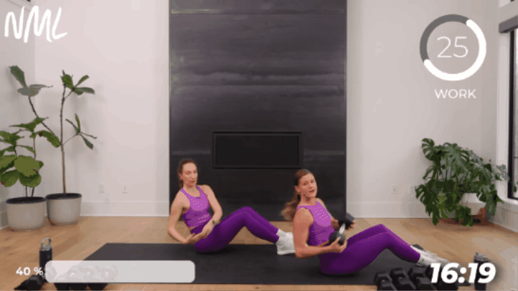two women performing seated twists as part of dumbbell full body workout