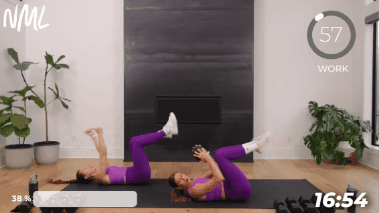 woman performing a reverse crunch with 1 dumbbell as part of full body strength workout