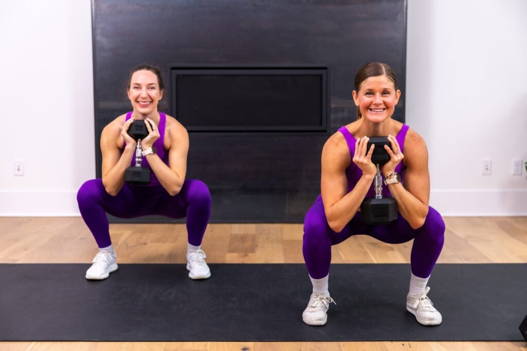 two women performing a goblet squat with a single heavy dumbbell as part of full body strength workout