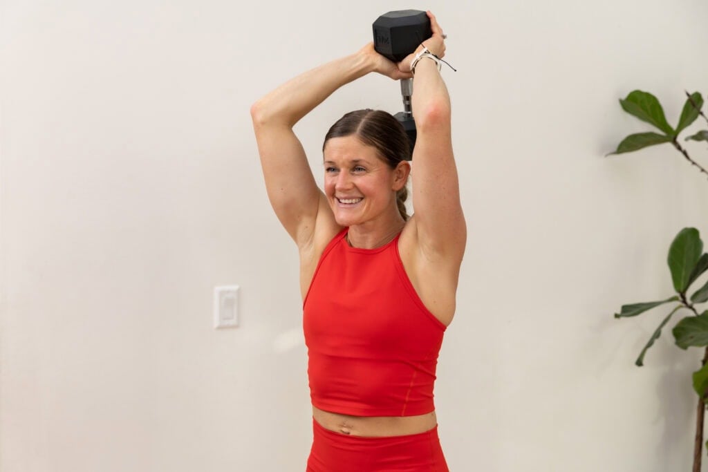 woman performing overhead tricep extensions with a dumbbell